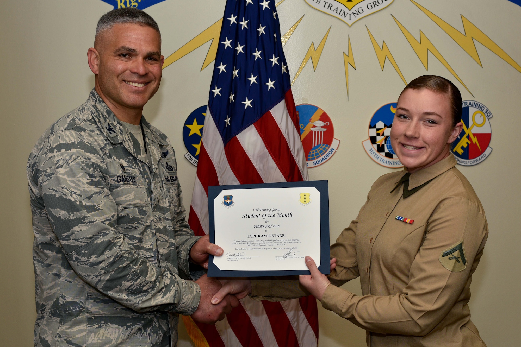 U.S. Air Force Col. Alex Ganster, 17th Training Group commander, presents the 17th TRG Student of the Month certificate to U.S. Marine Corps Lance Cpl. Kayle Starr, 316th Training Squadron trainee, in Brandenburg Hall on Goodfellow Air Force Base, Texas, March 2, 2018. The 316th TRS’s mission is to conduct U.S. Air Force, U.S. Army, U.S. Marine Corps, U.S. Navy and U.S. Coast Guard cryptologic, human intelligence and military training.  (U.S. Air Force photo by Senior Airman Randall Moose/Released)