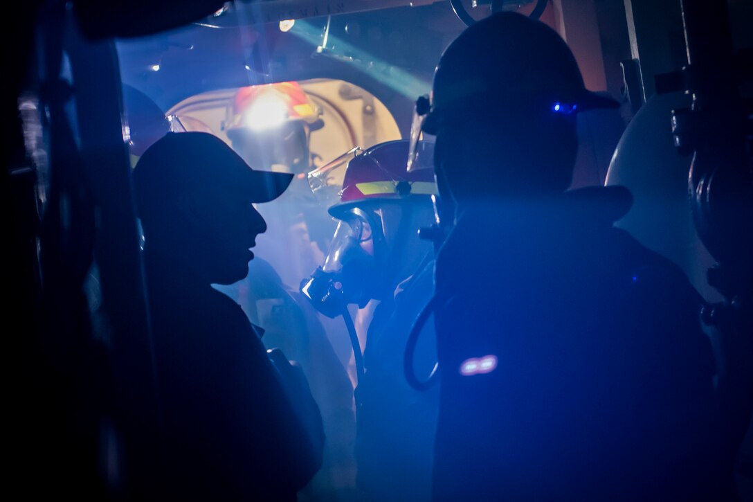 Sailors participate in a general quarters drill inside a guided-missile destroyer.