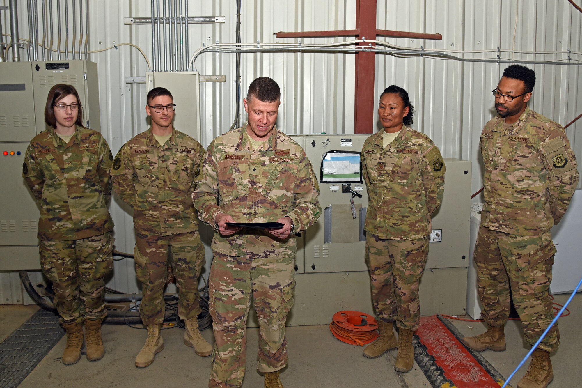 U.S. Air Force Brig. Gen. Kyle Robinson, 332nd Air Expeditionary Wing commander, reads highlights from the 332nd AEW Team of the Month award before presenting it to the 407th Expeditionary Communications Squadron Network Control Center at an undisclosed location in Southwest Asia March 5. During his visit, Robinson recognized key performers and toured construction sites. (U.S. Air Force photo by Staff Sgt. Joshua Edwards/Released)