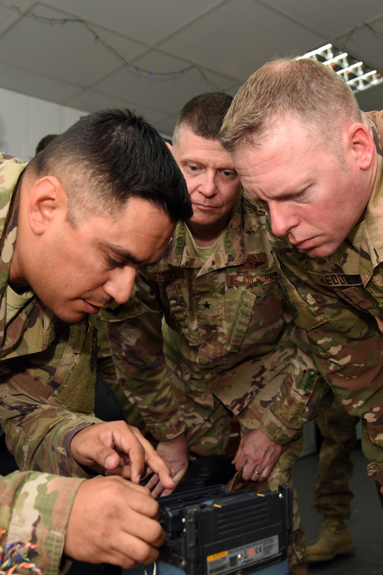 U.S. Air Force Tech. Sgt. Kristofer Canales, 407th Expeditionary Communications Squadron Cable Maintenance NCO in charge, shows Brig. Gen. Kyle Robinson, 332nd Air Expeditionary Wing commander, and Chief Master Sgt. Benjamin Hedden, 332nd command chief, how to fuse fiber optic cables together at an undisclosed location in Southwest Asia March 5. During the visit, Robinson and Hedden took the time to learn various duties and responsibilities of the 407th Air Expeditionary Group Airmen. (U.S. Air Force photo by Staff Sgt. Joshua Edwards/Released)