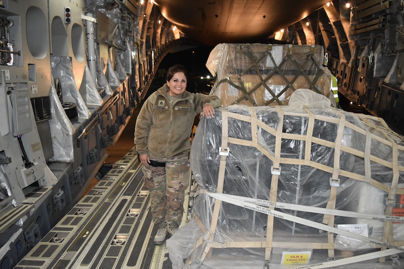 U.S. Army Staff Sgt. Bina K. Cheema stands with packaged Microwave Line-of-Sight radios aboard a C-17 Globemaster III.