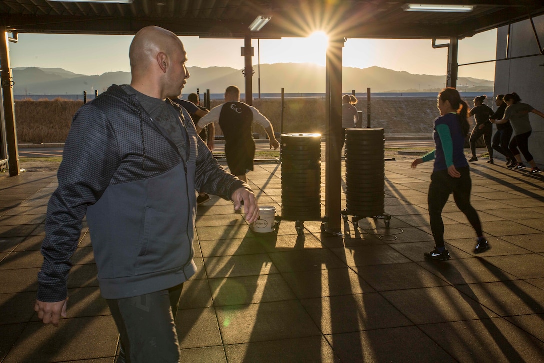 U.S. Marine Corps Chief Warrant Officer 3 Enrique Laguna, the Marine Corps Air Station (MCAS) Iwakuni telephone systems officer with Headquarters and Headquarters Squadron, leads dynamic warm-ups during a High Intensity Tactical Training (HITT) session at MCAS Iwakuni, Japan, March 6, 2018. Laguna instructs HITT classes three times a day to help Marines, and anyone else on the air station, achieve and surpass their fitness goals.