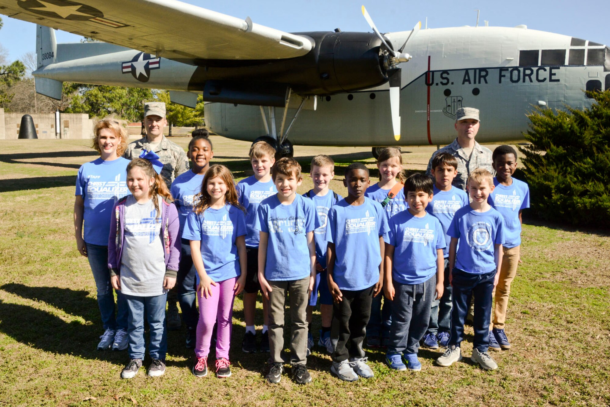 A group of fourth grade students from Southwest Christian Academy pose for a photo with (from left) their teacher Mika Santis, U.S. Air Force Reserve Tech Sgt. Malcolm Moe, historian, 913th Airlift Group and Senior Master Sgt. Jonathan Vansandt, the superintendent of inspections for the 913th AG,during a visit to Little Rock Air Force Base, Ark., Mar. 6, 2018. The students toured portions of the base as part of an effort to have young people know how military members live and work at Little Rock AFB.  (U.S. Air Force photo by Master Sgt. Jeff Walston/Released)