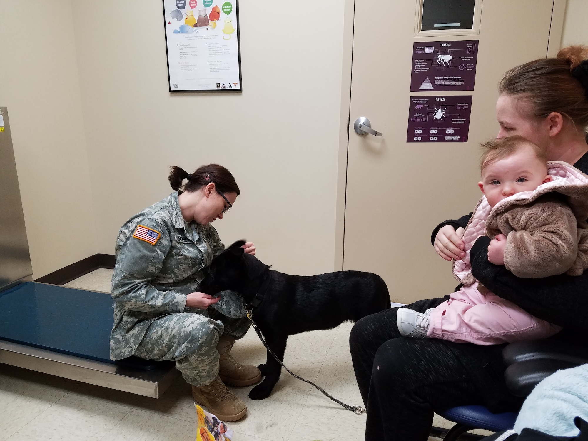 While still offering Sadie treats, Dr. Cassandra Kerwin checks her ears and lymph nodes. Sadie’s mom and sister, Jessica and Alexis Peck accompany her. (U.S. Air Force photo/Laura McGowan)