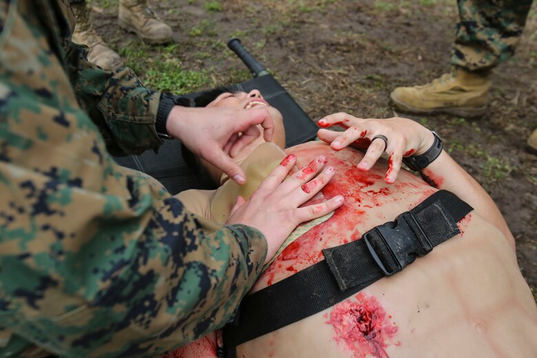 A U.S. Navy hospital corpsman with 2nd Medical Battalion, 2nd Marine Logistics Group, simulate applying a chest seal to a gunshot wound on a rubber suit used for training during a certification exercise at Camp Lejeune, N.C., March 1, 2018. The exercise was designed for shock trauma platoons and forward resuscitation surgical units to ensure the unit sustains medical proficiency and is capable of handling emergencies in future deployments.