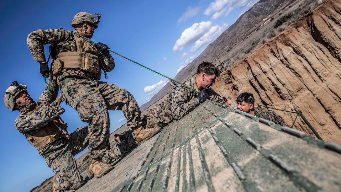 Marines, shown at an angle perform preventative maintenance to a girder bridge.