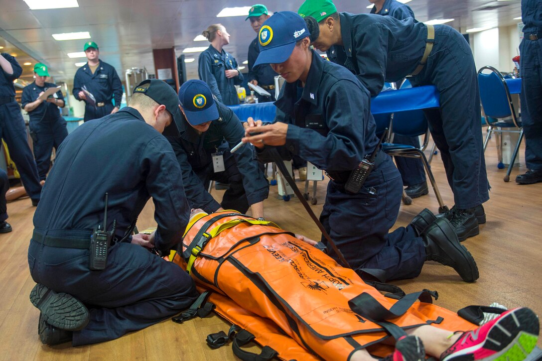 Sailors assess and prepare to transport a mock trauma patient.
