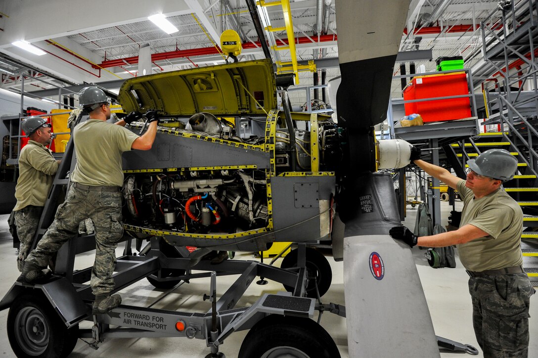 Tech. Sgt. Jeff Burgess, Senior Airman Daniel Phillis and Tech. Sgt. Steven Lew, all aerospace propulsion technicians with the 910th Aircraft Maintenance Squadron, secure a C-130H Hercules engine to an engine cart here.