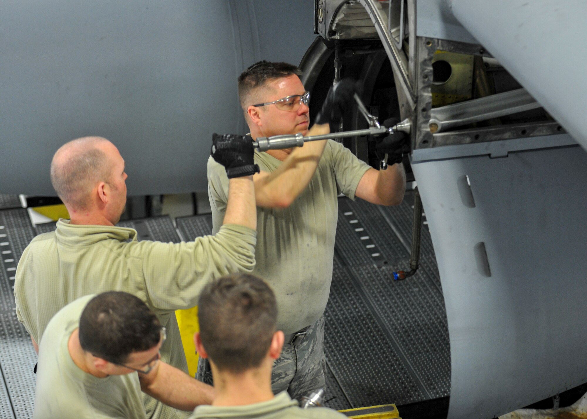 Tech. Sgt. Jeff Burgess and Tech. Sgt. Steven Lew, both aerospace propulsion craftsmen, use specialized tools to remove a guide cone from a C-130H Hercules aircraft engine mounting point, March 7, 2018.