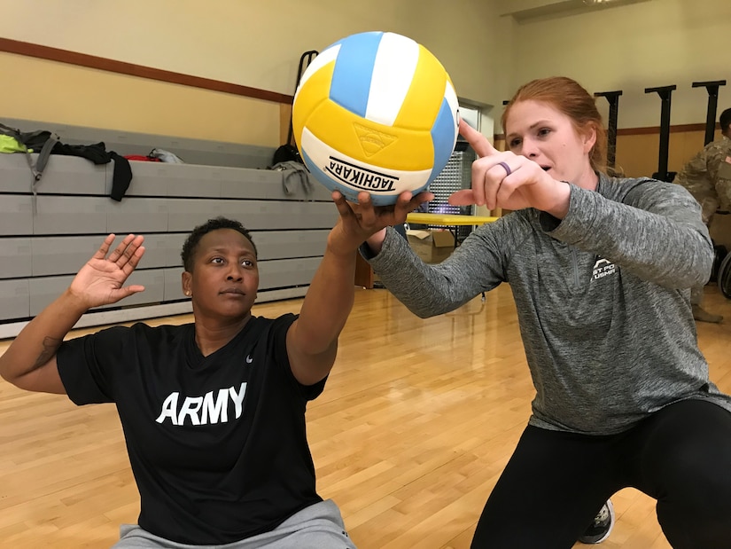 A volunteer sitting volleyball coach, helps a player with her float serve during practice for the Army Trials at Fort Bliss, Texas.