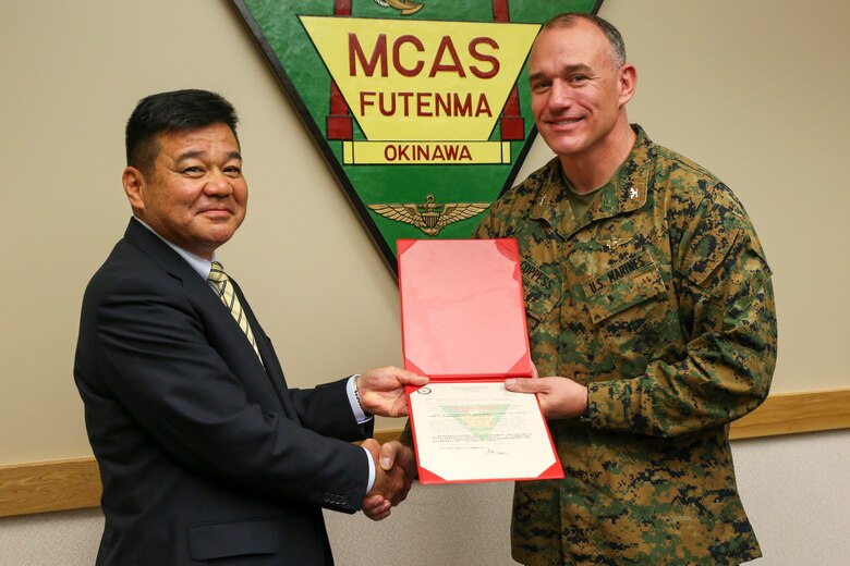 Police Chief Osamu Hamada, left, accepts a letter of appreciation from Col. Mark Coppess during an award ceremony March 8 on Marine Corps Air Station Futenma, Okinawa, Japan. Hamada was recognized for his excellent service to Ginowan City and MCAS Futenma. Hamada is retiring as the Ginowan City Police Department chief. Coppess is the commanding officer of MCAS Futenma. (U.S. Marine Corps photo by Pfc. Nicole Rogge)