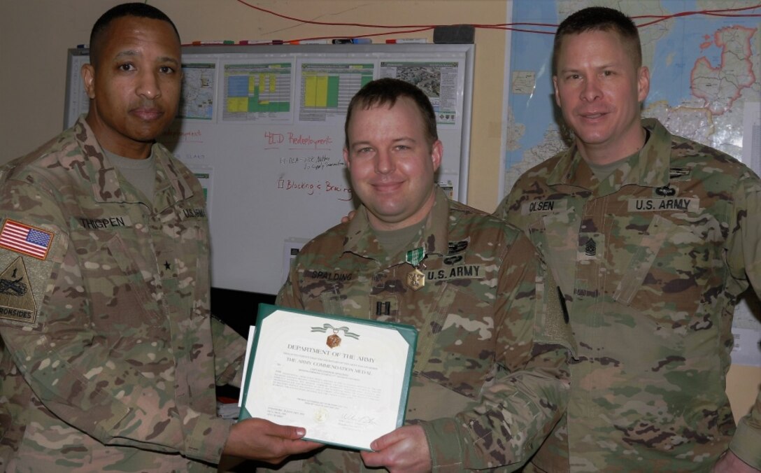 Army Capt. Jason M. Spalding, center, 21st Theater Sustainment Command liaison officer Mission Command Element receives an Army Commendation Medal from Army Brig. Gen. William L. Thigpen, left, the 4th Infantry Division’s deputy commanding general, and Army Command Sgt. Maj. Eric B. Olsen, the division/MCE sergeant major, at the MCE’s headquarters in Poznan, Poland, Feb. 19, 2018. Spalding has worked during his tour to improve living and working conditions for soldiers in support of the Atlantic Resolve mission. Army photo by Staff Sgt. Scott J. Evans