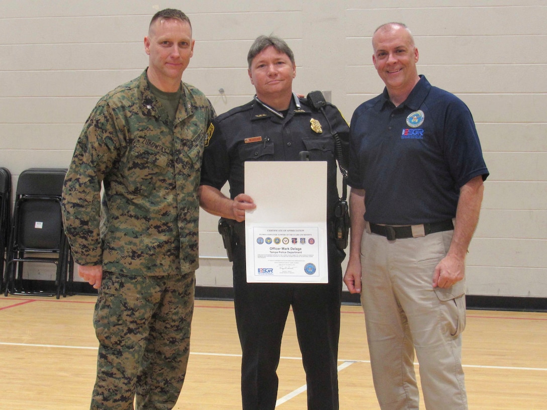 Lt. Col. Sean Zukowsky (left), commanding officer of 4th Assault Amphibian Battalion, 4th Marine Division, Marine Forces Reserve, and Dale Hoffman (right), volunteer at the Employer Support of the Guard and Reserve, present officer Mark Delage (center) with a letter of appreciation for his support to the Reserve Force members on March 2, 2018, in Tampa Fla.
