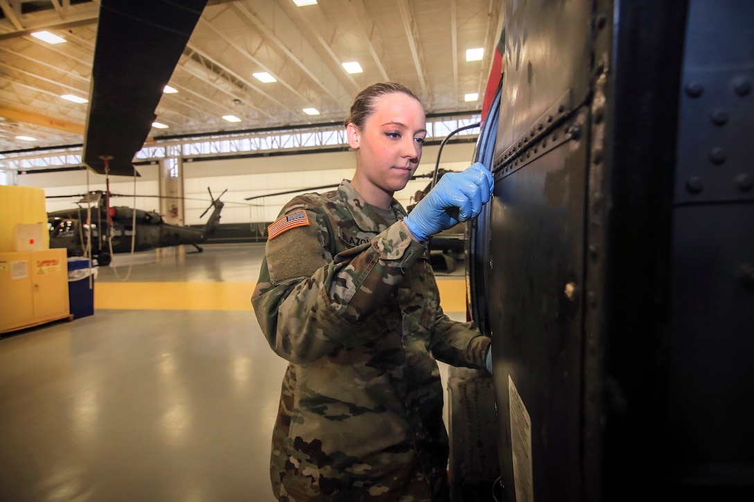 A soldier performs maintenance checks on a helicopter.