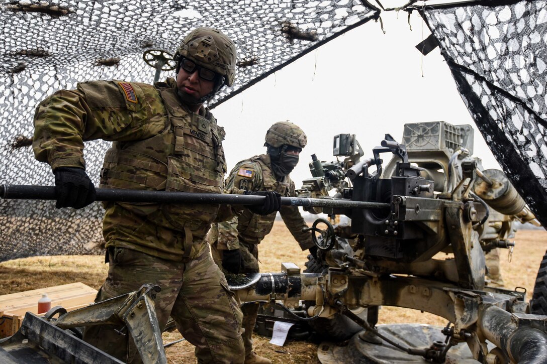 Soldiers prepare to fire a howitzer.