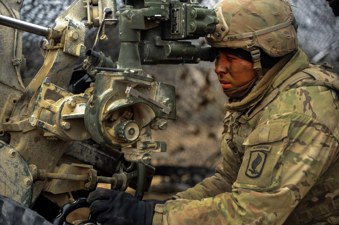 A soldier sights in a howitzer.