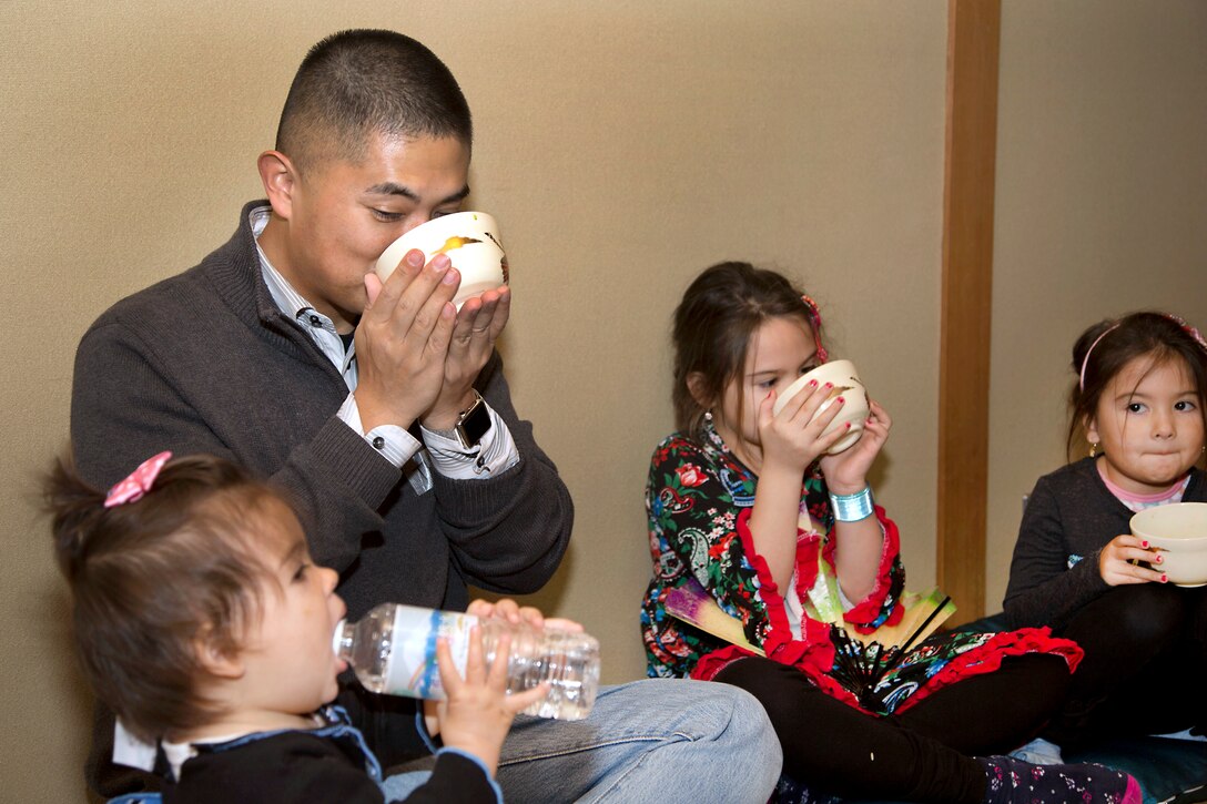 An adult drinks tea with three children.