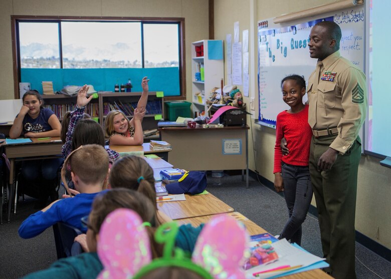 GySgt. Jared R Wright, Marine Training Unit Staff Non Commissioned Officer in Charge, Marine Training Unit, and daughter, Su'Myah K. Wright answer questions of students in support of Read Across America at Friendly Hills Elementary School in Joshua Tree, Calif., on March 2, 2018.  Read Across America is an annual reading motivation and awareness program that calls for every child in every community to celebrate reading. (U.S. Marine Corps Photo by Cpl. Francisco J. Britoramirez)