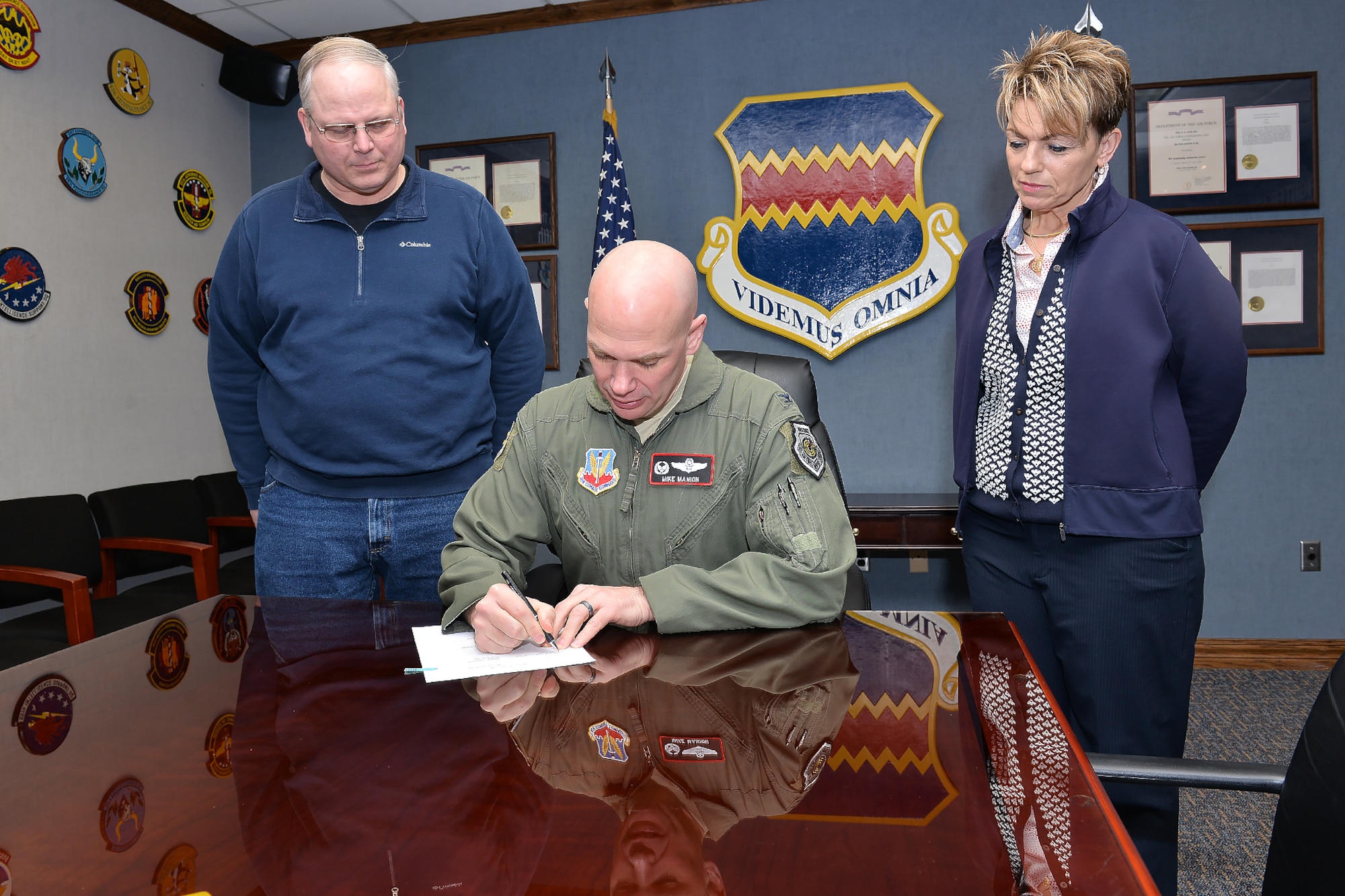 Timothy Slobodnik (L), 55th Civil Engineer Squadron and AFGE Local Chapter 1486 president and Shay Caris (R), 55th FSS Civilian Personnel Flight Labor Relations officer watch Col. Michael Manion, 55th Wing commander, sign a new collective bargaining agreement on March 7 at 55th Wing headquarters on Offutt Air Force Base, Nebraska.