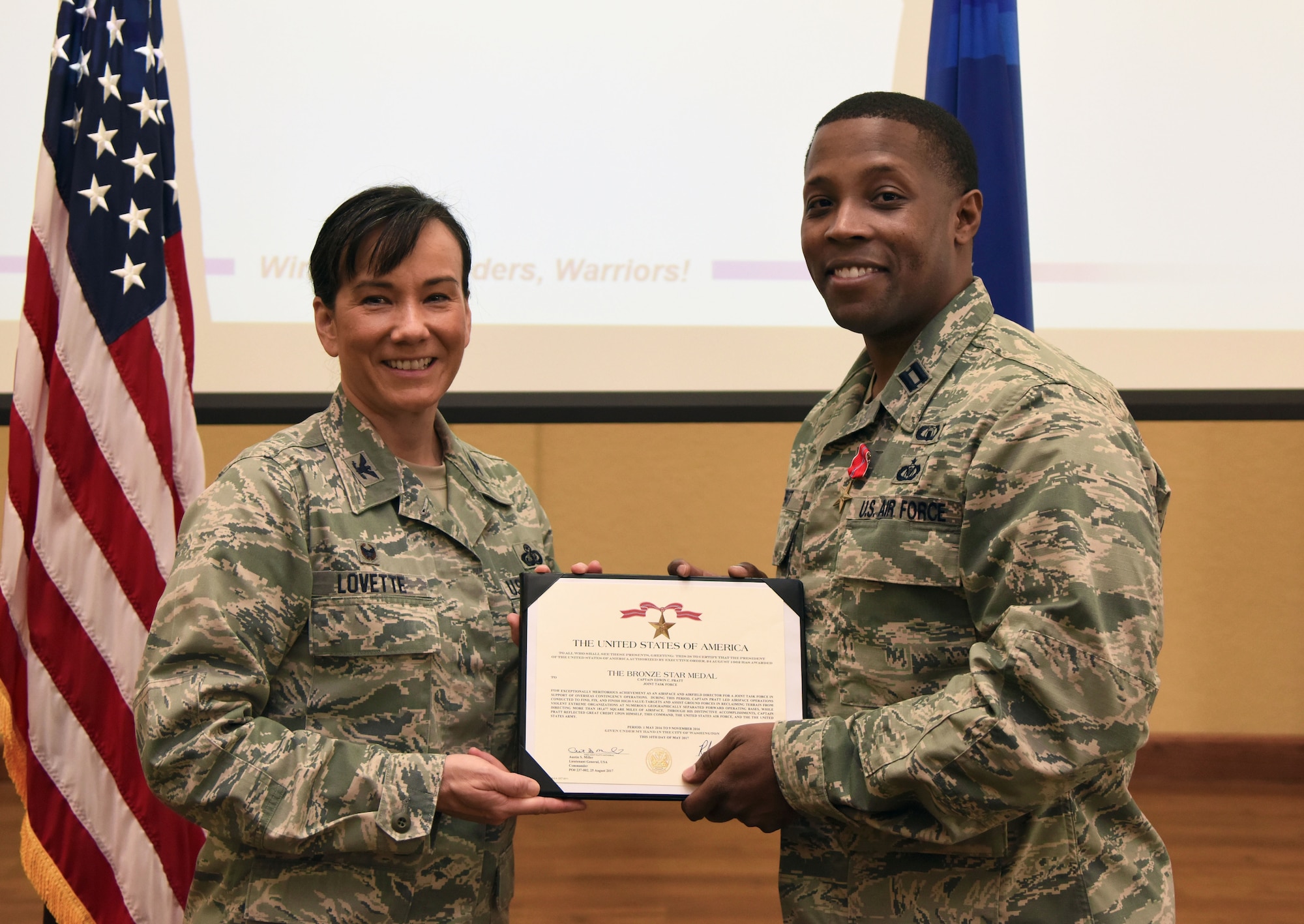 Col. Debra Lovette, 81st Training Wing commander, presents Capt. Edwin Pratt, 81st TRW executive officer, with a certificate of recognition during a commander’s all-call at the Bay Breeze Event Center March 5, 2018, on Keesler Air Force Base, Mississippi. Pratt was presented with a Bronze Star for meritorious achievement May 2016, through Nov. 2016. (U.S. Air Force photo by Kemberly Groue)