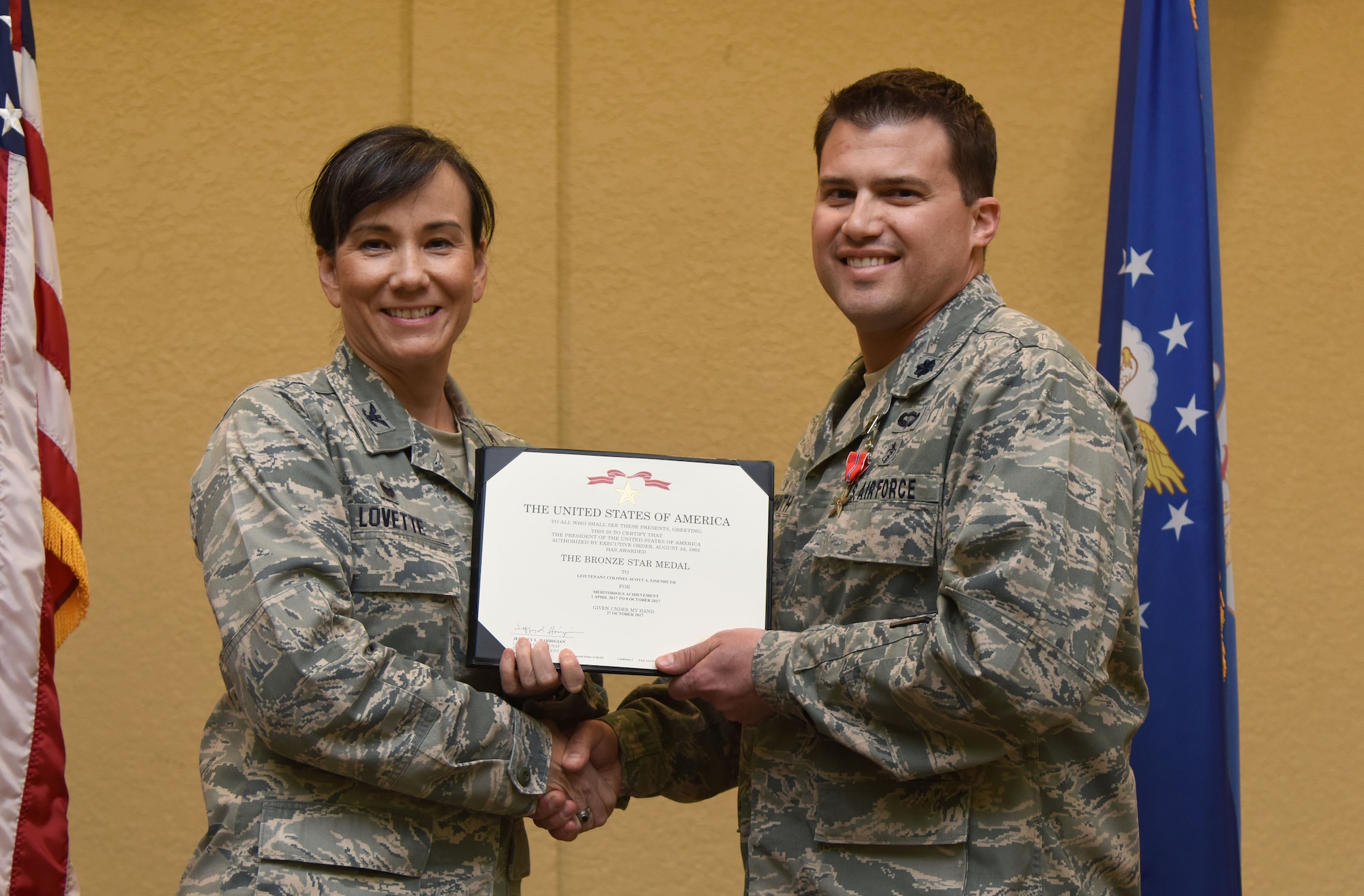 Col. Debra Lovette, 81st Training Wing commander, presents Lt. Col. Scott Eisenhuth, 81st Surgical Operations Squadron orthopedic surgeon, with a certificate of recognition during a commander’s all-call at the Bay Breeze Event Center March 5, 2018, on Keesler Air Force Base, Mississippi. Eisenhuth was presented with a Bronze Star for meritorious achievement while assigned to a surgical team deployed to Iraq, April 2017, through Oct. 2017. (U.S. Air Force photo by Kemberly Groue)
