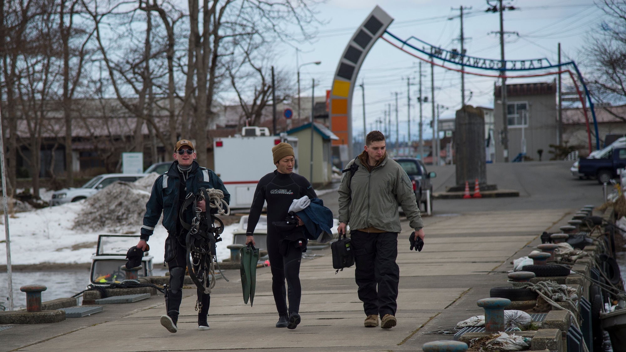 U.S. Navy divers assigned to Commander, Fleet Activities Yokosuka and Sasebo, walk to the pier at Lake Ogawara prior to clean up efforts in Tohoku Town, Japan, March 10, 2018.