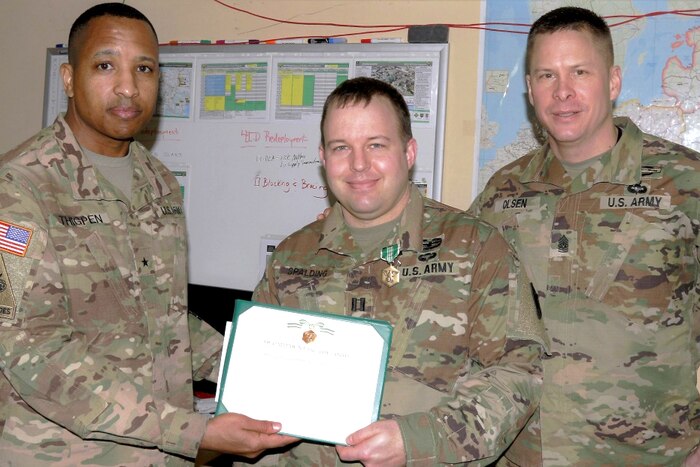 Three service members pose for a photograph with two holding a certificate.