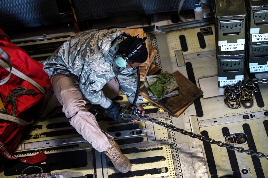 An airman tightens a cable securing a Humvee.