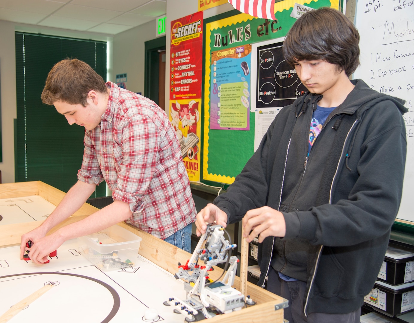 Cole High School students Mitchell Hafer (left) and Henry Yowell (right) set up a robotics competition board and robot in a classroom. Both students, members of the Cole robotics team, will be competing in the Texas Computer Educators Association State Robotics Challenge Contest April 7 at Hutto High School, near Austin.