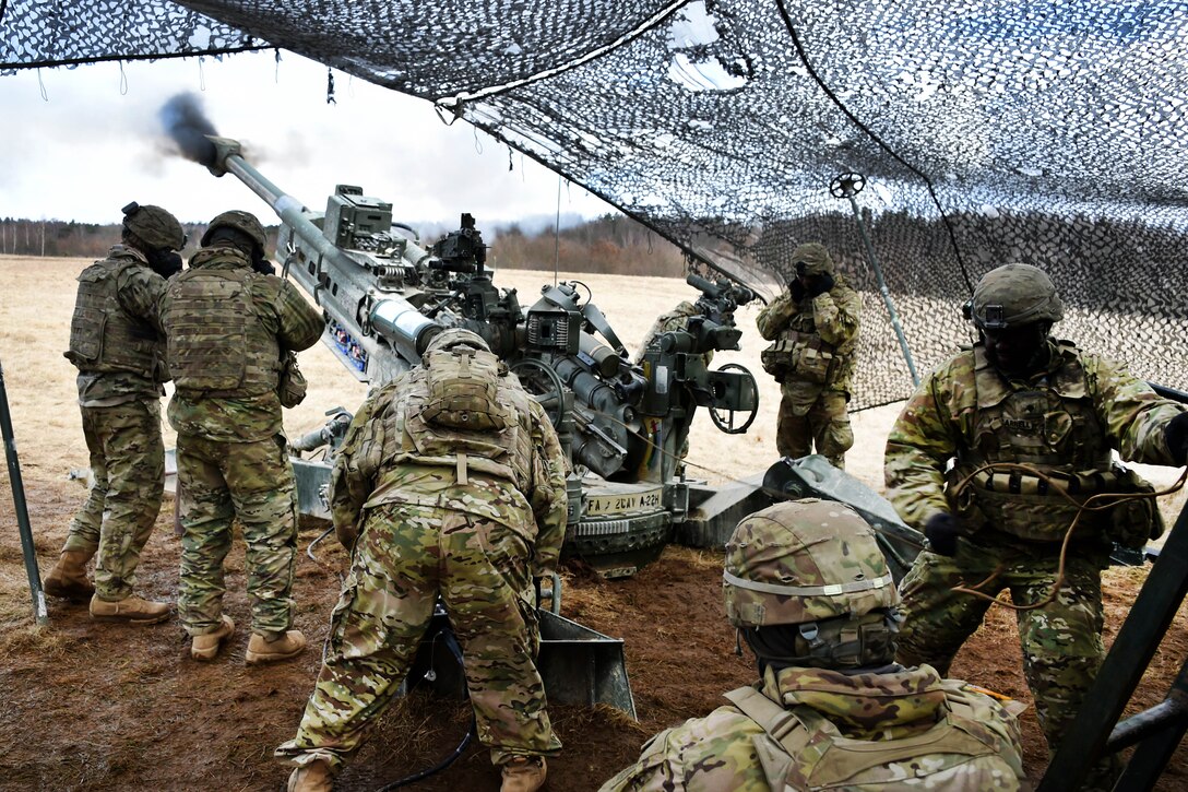 Soldiers fire a M777 howitzer.