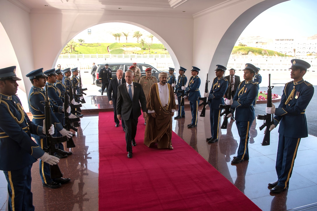 Defense Secretary James N. Mattis walks with the Omani Defense Affairs Minister on a red carpet.