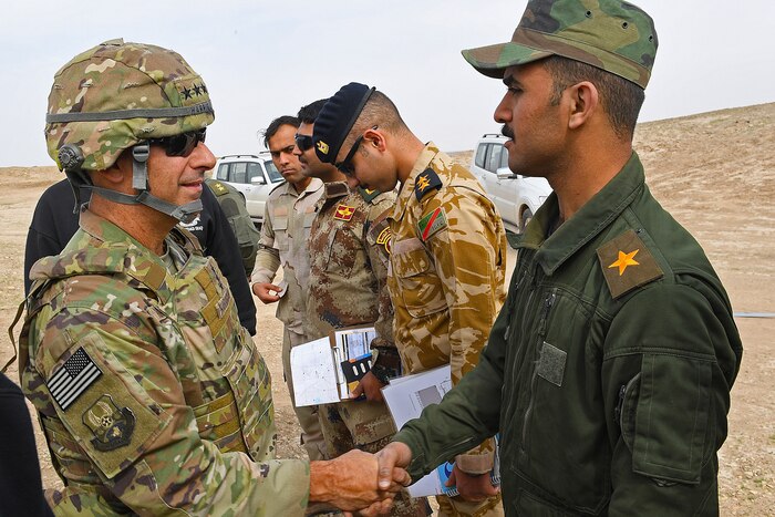 An airman shakes hands with an Iraqi Air Force student.