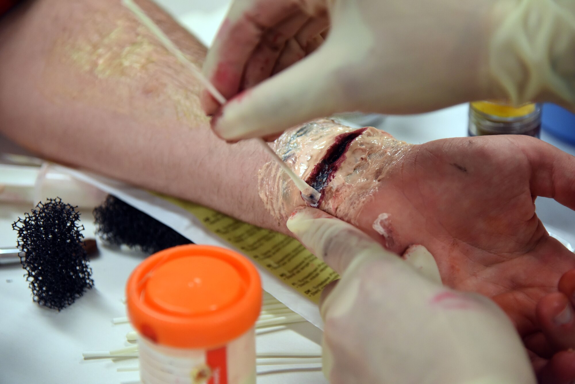 Staff Sgt. Dominque Mason, 81stst Medical Operations Squadron neurodiagnostic technologist, applies moulage to Staff Sgt. Matthew Clinesmight, 81st Security Forces Squadron evaluator, during a training session at Allee Hall March 8, 2018, on Keesler Air Force Base, Mississippi. The session was held to teach volunteers how to apply moulage on exercise “casualties” to provide emergency responders with a more realistic training experience. (U.S. Air Force photo by Kemberly Groue)