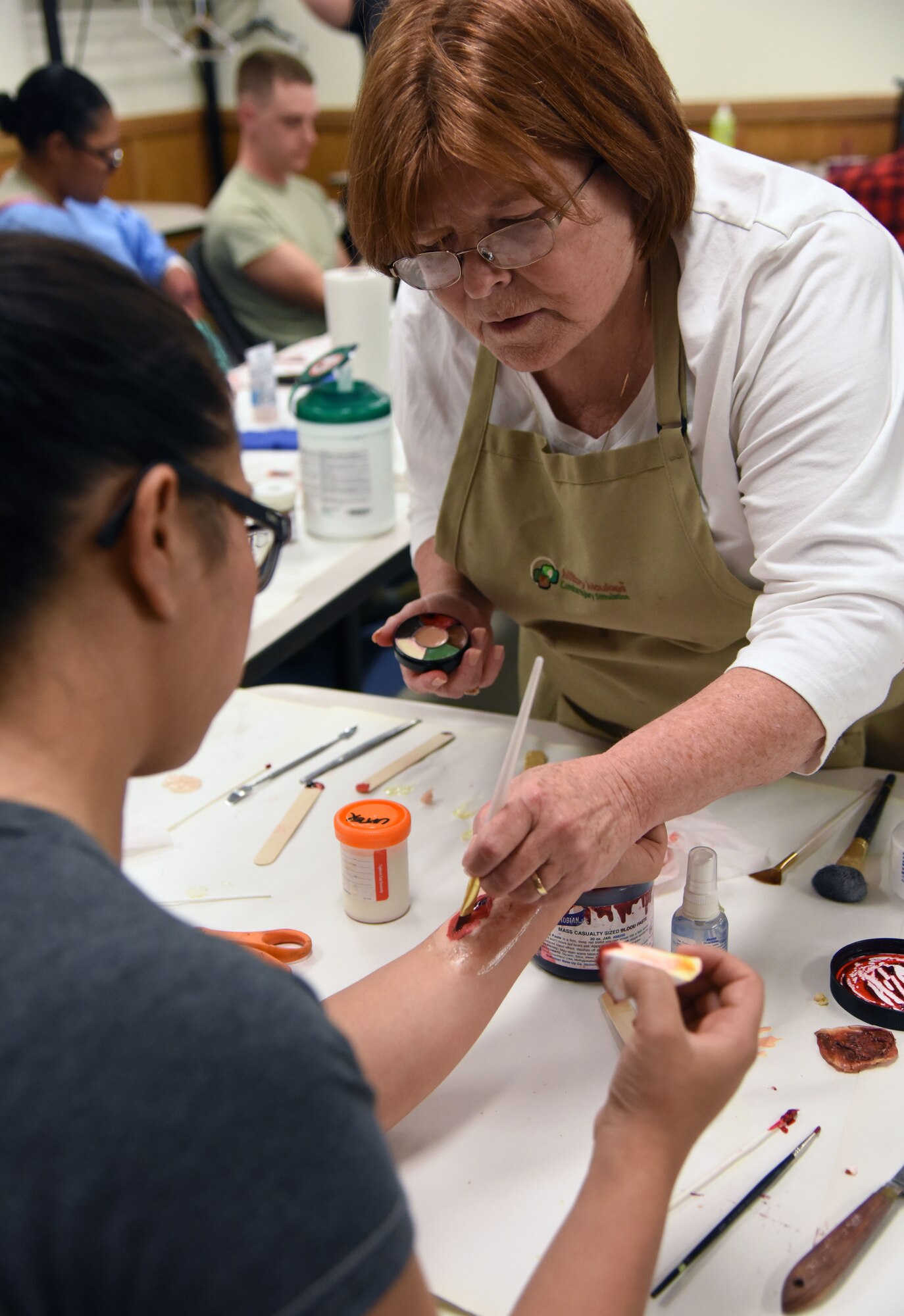 Regina Parker, 81st Medical Operations Squadron mental health secretary and moulage co-team lead, applies moulage to Mayra Guerra, 81st Training Wing wing inspection team manager, during a training session at Allee Hall March 8, 2018, on Keesler Air Force Base, Mississippi. The session was held to teach volunteers how to apply moulage on exercise “casualties” to provide emergency responders with a more realistic training experience. (U.S. Air Force photo by Kemberly Groue)