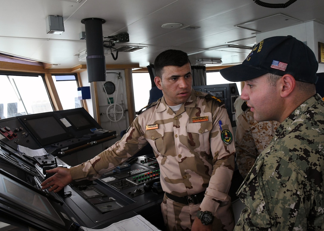 (Feb. 21, 2018) Iraqi navy 1st Lt. Ahmad Gabar (left), second mate of Iraqi offshore support vessel Al Basra (401), explains Al Basra’s bridge watch stations to Gunner’s Mate Seaman Steven Saikaly, a Sailor assigned to coastal patrol ship USS Hurricane (PC 3), during a trilateral exercise with Iraq and Kuwait. The exercise is a surface engagement between the U.S. Navy, Iraqi navy, Kuwaiti navy and coast guard focused on improving proficiency in maritime security tactics to help ensure the freedom of navigation throughout the U.S. 5th Fleet area of operations. (U.S. Navy photo by Mass Communication Specialist 1st Class Bryan Neal Blair/Released)