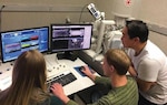 IMAGE: CHARLOTTESVILLE, Va. - University of Virginia students investigate material properties with a microscope. The students and their professors teamed up with Naval Surface Warfare Center Dahlgren Division (NSWCDD) engineers and scientists through the Naval Engineering Education Consortium (NEEC) to develop a better understanding of the capabilities and limitations of additive manufacturing (3D printing).  "The research that the University of Virginia is conducting is an important examination of the microstructure and mechanical properties of alloys relevant to the Navy produced by state of the art additive manufacturing techniques," said Ricky Moore, an NSWCDD engineer and mentor to the students. "Understanding these properties is paramount as the Navy begins to design, develop, produce, and field components and systems produced with additive manufacturing to improve performance and availability of systems in the Fleet. Without it, much of the promise of additive manufacturing will be out of reach."