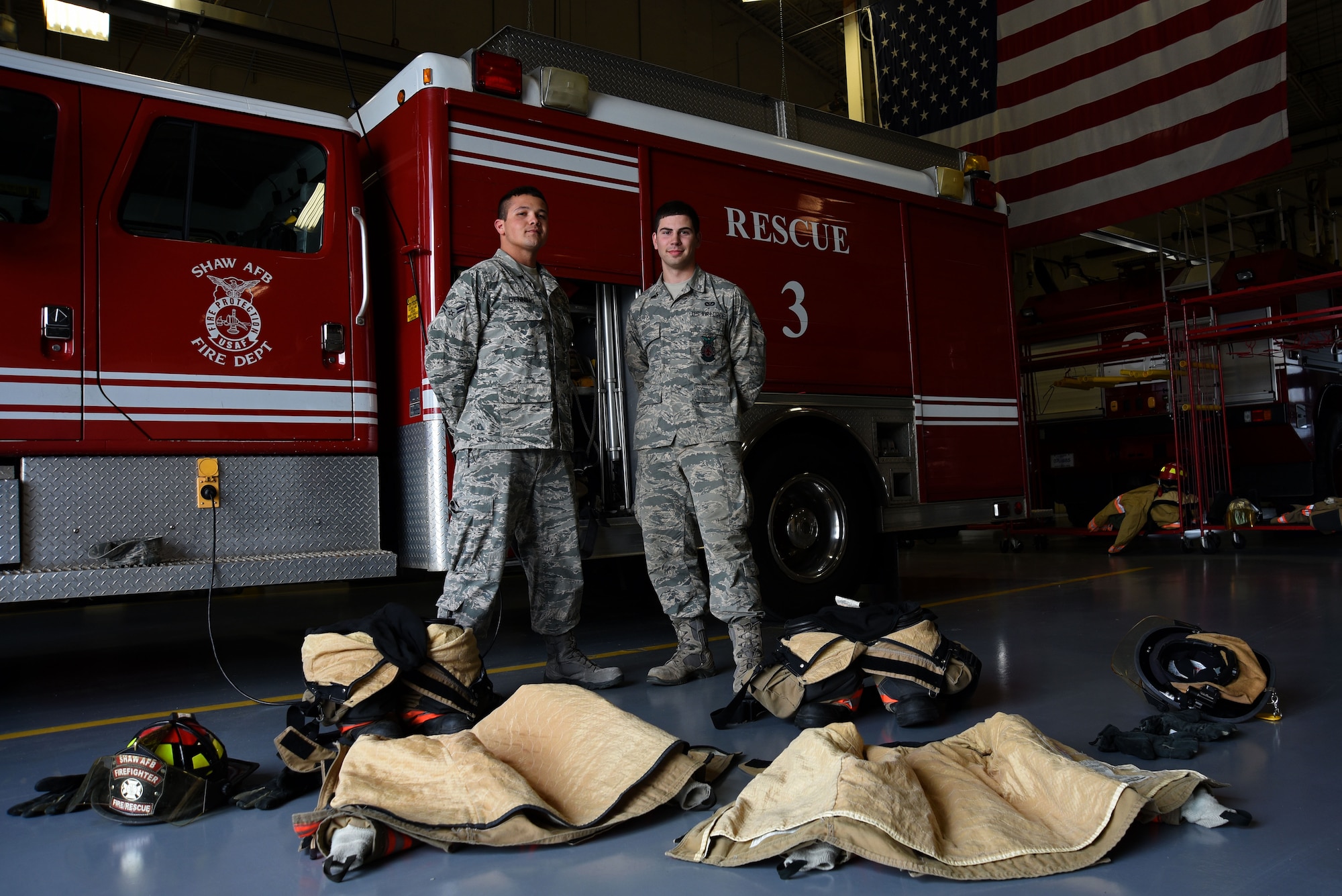 U.S. Air Force Airmen 1st Class Nicholas Denning, left, and Trevor Britt, 20th Civil Engineer Squadron firefighters, stand behind their gear at Shaw Air Force Base, S.C., March 8, 2018.