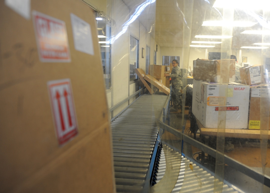 A cardboard box sits on a conveyor belt in a warehouse.