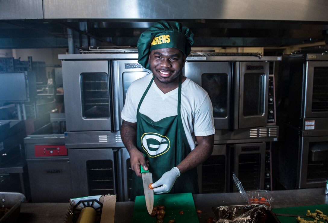 U.S. Army Specialist Kevron Usher, culinary specialist with Task Force Talon's  E Battery, 3rd Air Defense Artillery Regiment, pauses for a photo March 8, 2018, at Magellan Inn Dining Facility, Guam. Usher joined Airmen in the quarterly "Top Chef Competition" at Magellan Inn and sported his Green Bay Packers cooking gear in celebration of the occasion. (U.S. Air Force photo by Staff Sgt. Alexander W. Riedel)