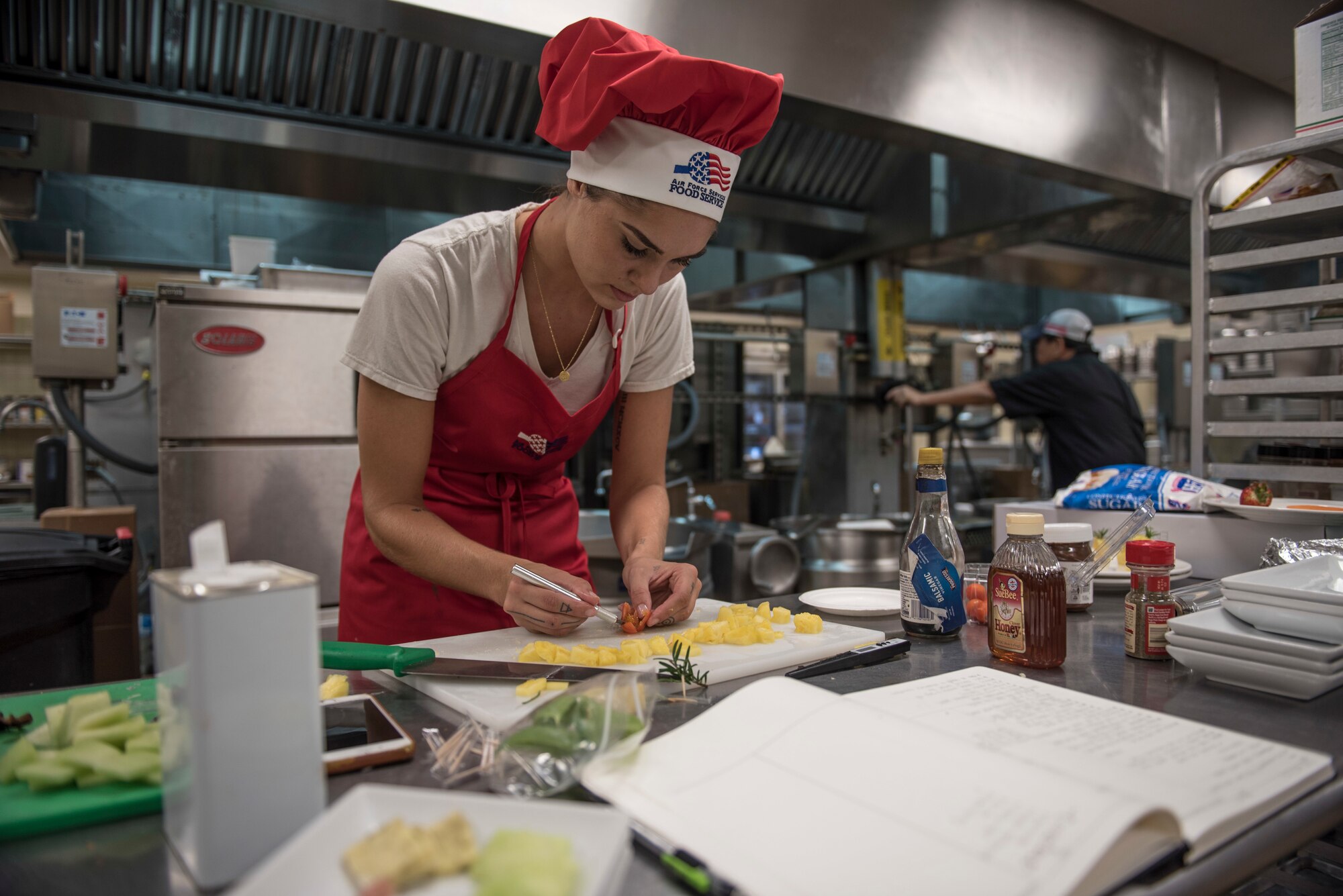 U.S. Air Force Senior Airman Caroline Spellen, 36th Force Support Squadron food services supervisor, cuts a cherry tomato into a decorative flower March 8, 2018, at Magellan Inn Dining Facility, Guam. Spellen won the quarterly "Top Chef Competition" at Magellan Inn, which tasked military cooks to create interesting dishes with mandatory ingredients provided in a "mystery box." (U.S. Air Force photo by Staff Sgt. Alexander W. Riedel)