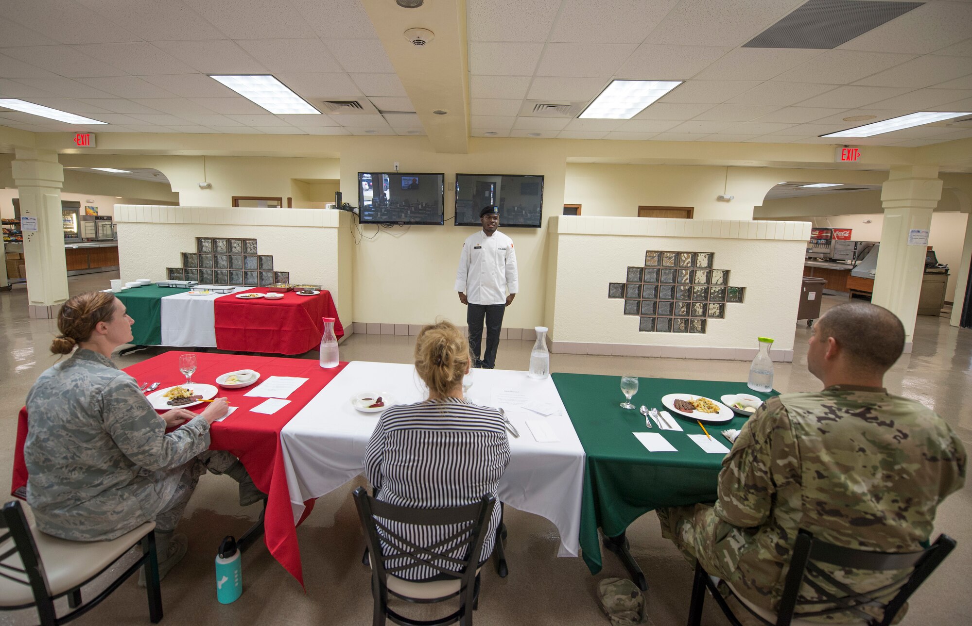 At front, U.S. Army Specialist Kevron Usher, culinary specialist with Task Force Talon's  E Battery, 3rd Air Defense Artillery Regiment, stands before a panel of Air Force, Army and civilian leaders during the quarterly Top Chef competition March 8, 2018, at Andersen Air Force Base, Guam. Magellan Inn dining facility hosts the quarterly competition to recognize its top culinary specialists and food services Airmen, and reward the Top Chef with a competitive internship at a local resort hotel. (U.S. Air Force photo by Staff Sgt. Alexander W. Riedel)