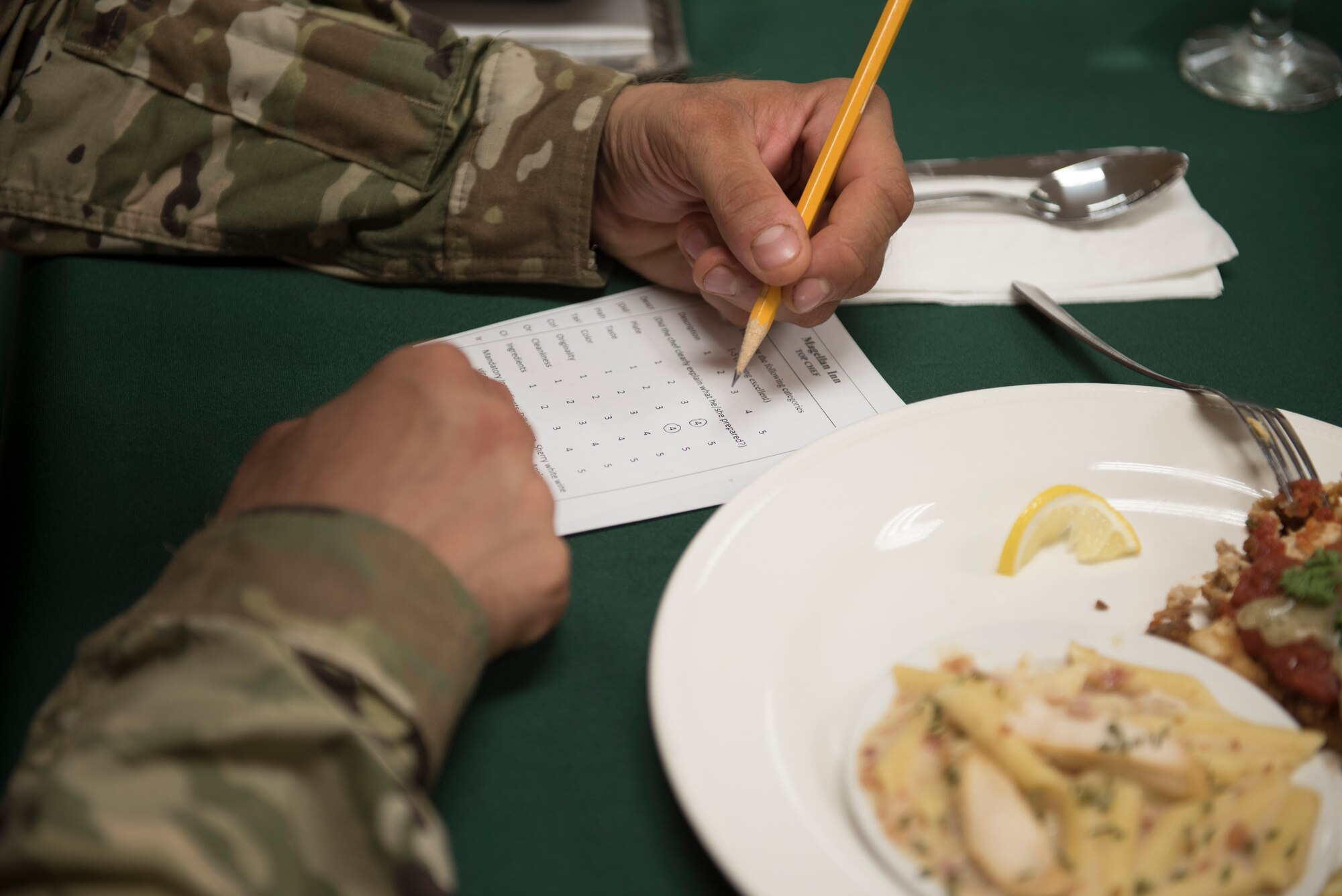 A U.S. Army culinary NCO grades a meal during a quarterly Top Chef competition March 8, 2018, at Andersen Air Force Base, Guam. Army and Air Force food services specialists assigned to Margellan Inn Dining Facility competed in a timed competition to prepare creative dishes with a selection of ingredients issued at the beginning of the competition. (U.S. Air Force photo by Staff Sgt. Alexander W. Riedel)