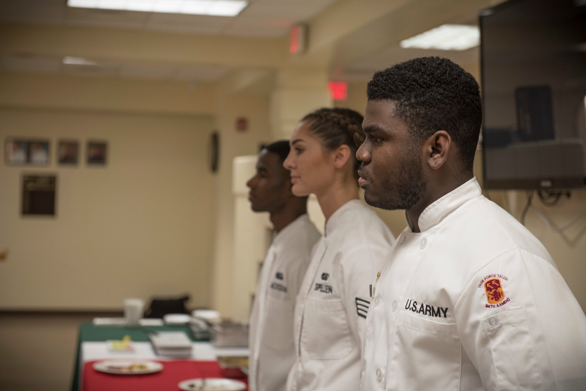 From the right, U.S. Army Specialist Kevron Usher, U.S. Air Force Senior Airman Caroline Spellen and Airman 1st Class Tyrell Jackson stand before a panel of judges during the quarterly Top Chef competition March 8, 2018, at Andersen Air Force Base, Guam. Magellan Inn dining facility hosts the quarterly competition to recognize its top culinary specialists and food services Airmen, and reward the Top Chef with a competitive internship at a local resort hotel. (U.S. Air Force photo by Staff Sgt. Alexander W. Riedel)