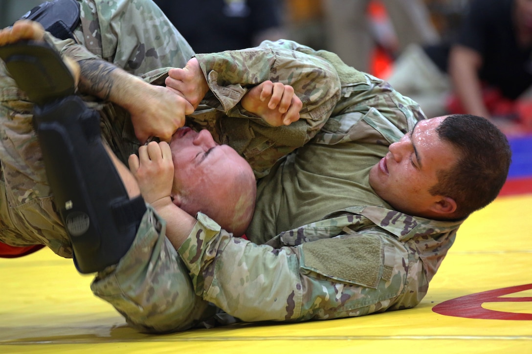 A soldiers puts a submission hold on his opponent.