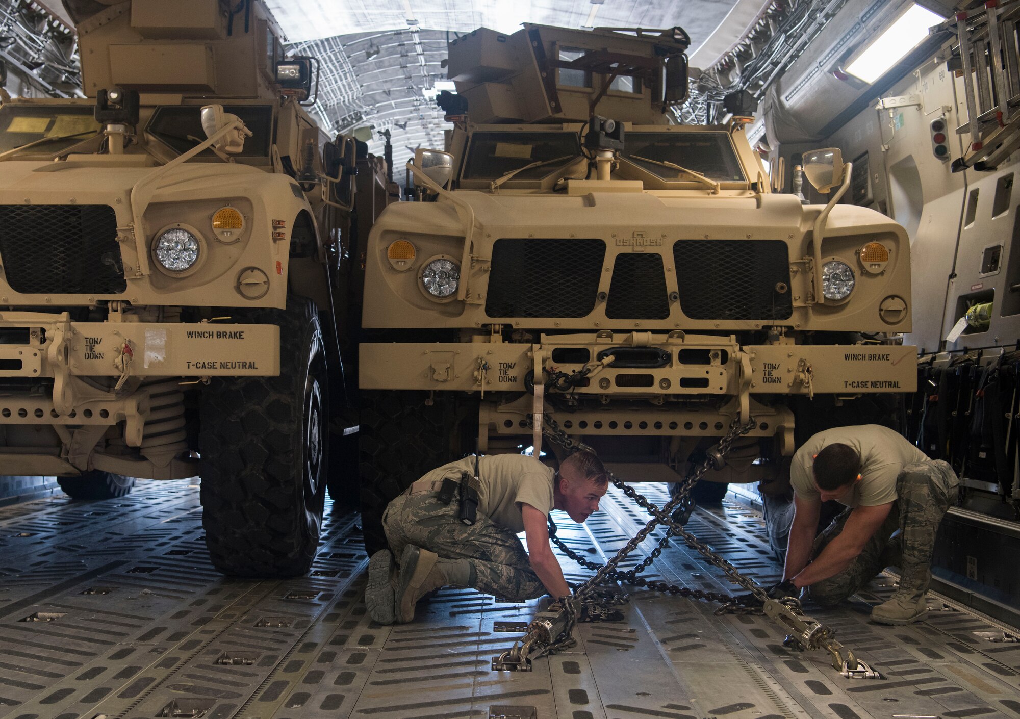 Tech. Sergeants Josiah Bourke and Nick Akins, 332nd Expeditionary Logistics Readiness Squadron air transportation specialists, secure mine-resistant ambush protected vehicles for transportation onto a C-17 Globemaster III at an undisclosed location in Southwest Asia March 7, 2018.