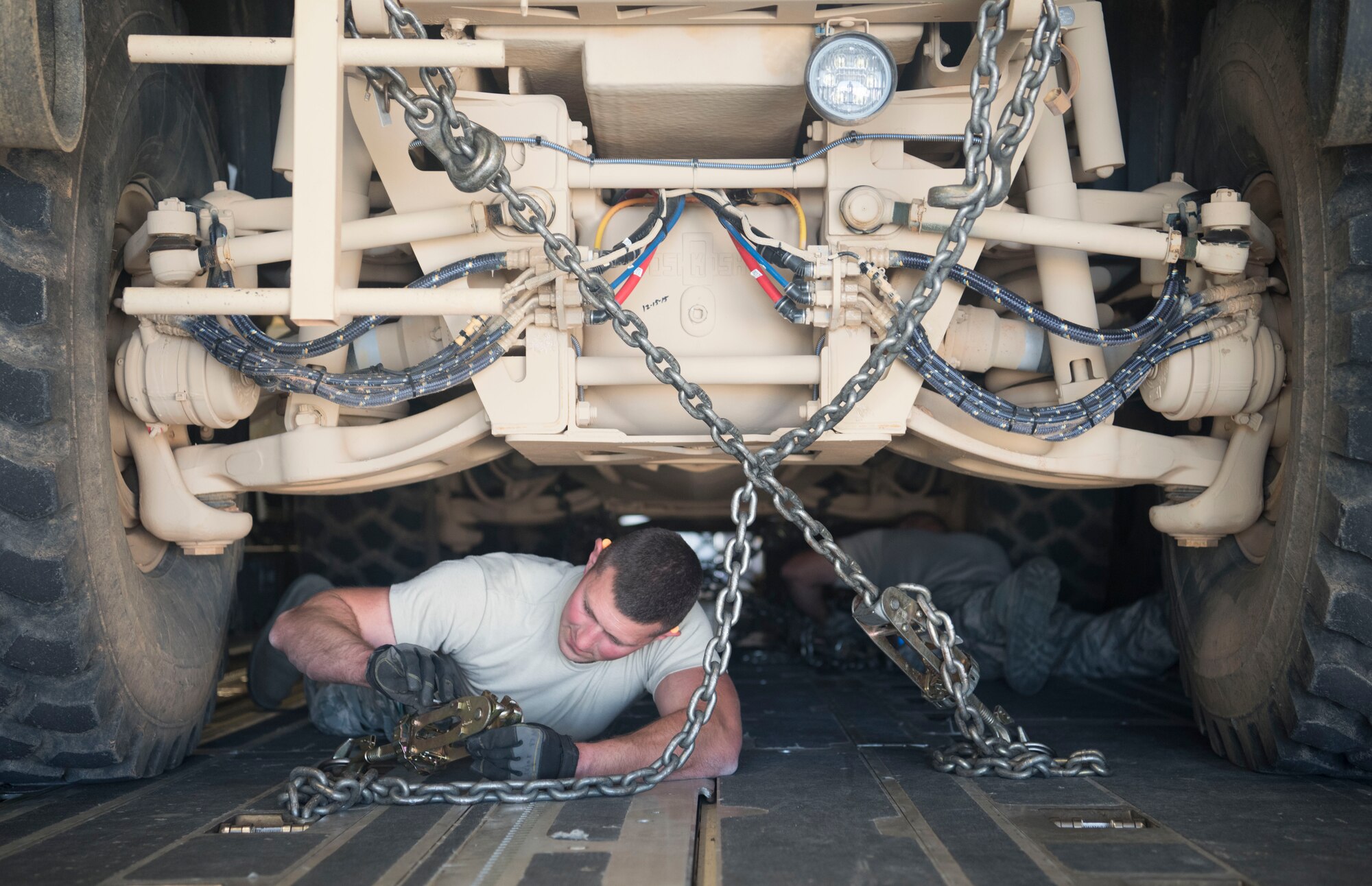 Tech. Sgt. Josiah Bourke, 332nd Expeditionary Logistics Readiness Squadron air transportation specialist, secures a mine-resistant ambush protected vehicle with chains for transportation onto a C-17 Globemaster III at an undisclosed location in Southwest Asia March 7, 2018.