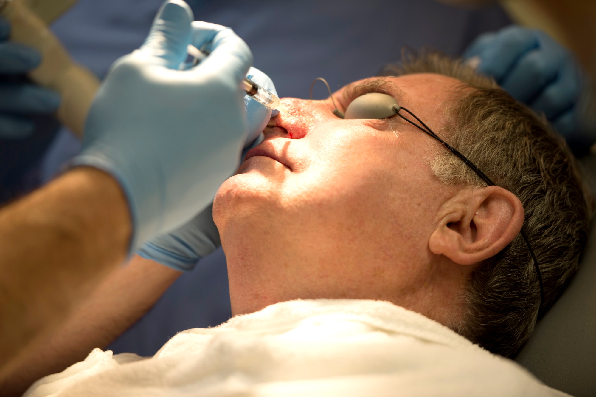 Maj. (Dr.) Thomas Beachkofsky, dermatology element leader assigned to the 6th Medical Group, injects lidocaine into the nose of a dermatology patient, to numb the surrounding area during a laser treatment at MacDill Air Force Base, Fla., March 9, 2018.