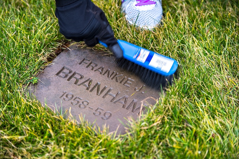A Kaiserslautern Military Community member cleans a gravestone at the American Kindergraves in Kaiserslautern, Germany, March 10, 2018. From 1952 to 1971, 451 American infants lost their lives at birth or shortly after birth at local hospitals. Families buried the remains of those children in a cemetery near the U.S. Army Daenner Kaserne and named the memorial Kindergraves. (U.S. Air Force photo by Senior Airman Devin Boyer)