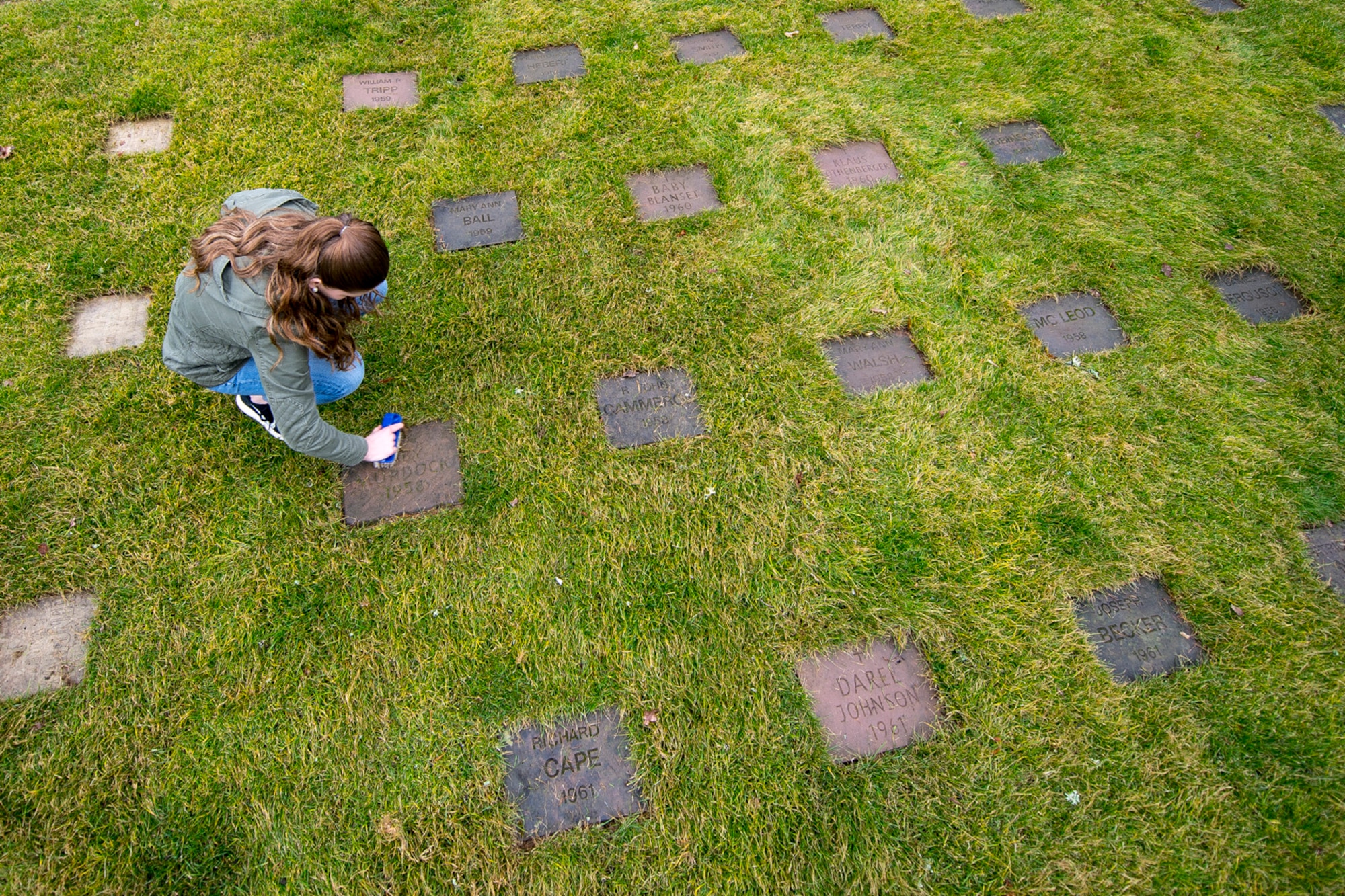 Cortlee Austin, Kaiserslautern Military Community member, cleans a gravestone at the American Kindergraves in Kaiserslautern, Germany, March 10, 2018. Between March and November, U.S. service members from the KMC area volunteer on a bi-weekly basis to maintain the Kindergraves by cleaning, mowing and placing flowers on graves. (U.S. Air Force photo by Senior Airman Devin Boyer)