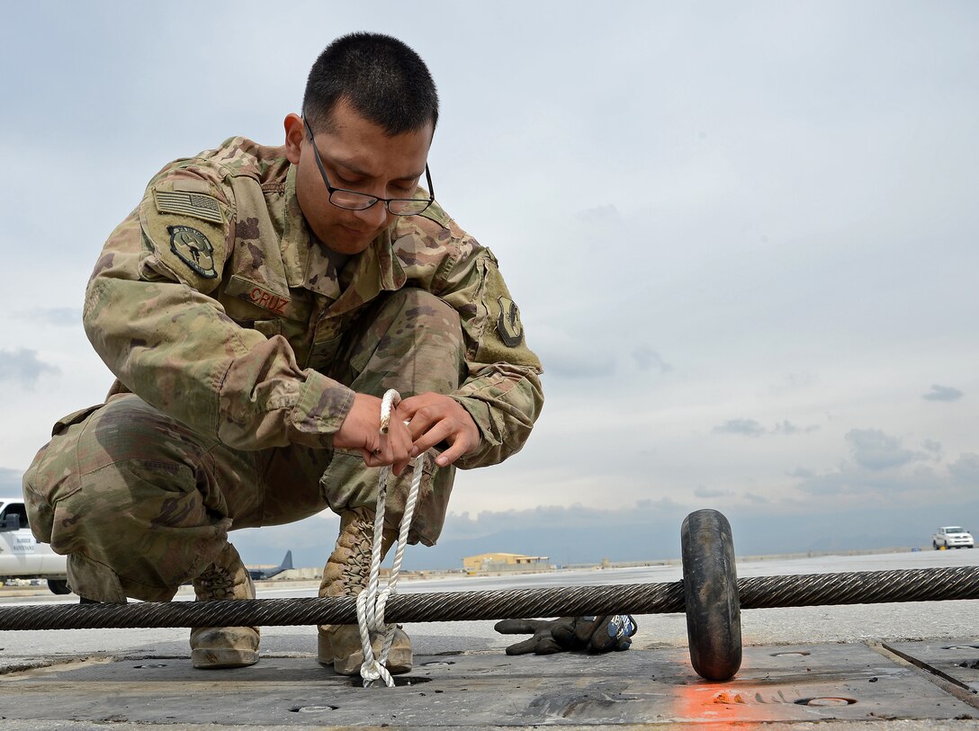 Airman Rene Cruz, 455th Expeditionary Civil Engineer Squadron power production engineer, ties down part of the Aircraft Arrest System Mar. 3, 2018 at Bagram Airfield, Afghanistan.